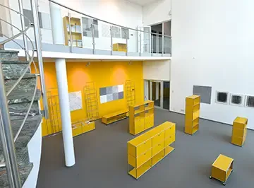 Blick in das zweigeschossige Foyer mit gelben USM-Haller-Möbeln und Kunstwerken
