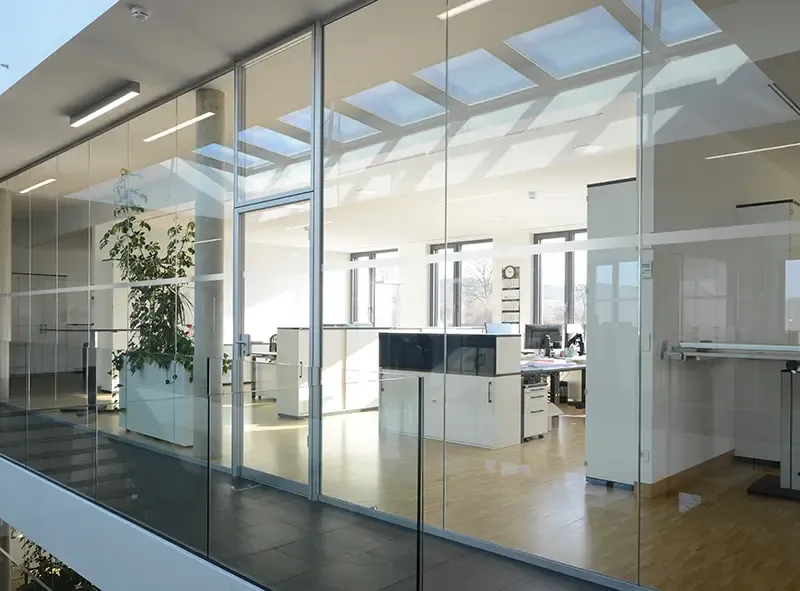 Verglaste Bürozeile unter Oberlichtern mit Blick auf die Arbeitsplätze