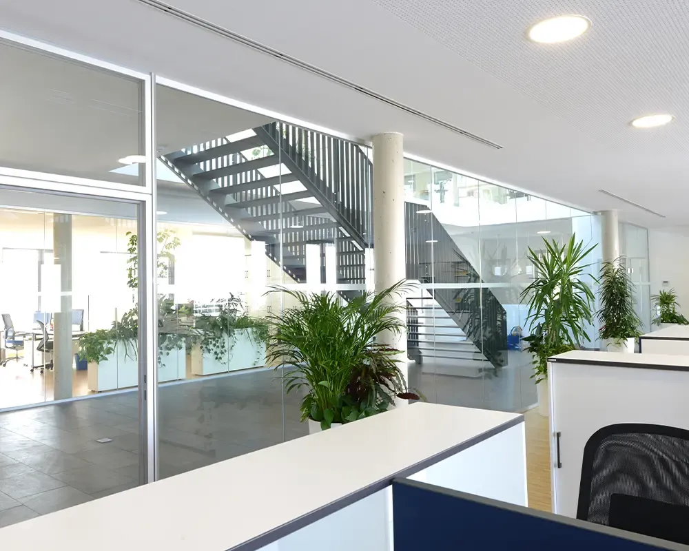 Offener Bürobereich mit Pflanzen und einer schwarzen Stahltreppe