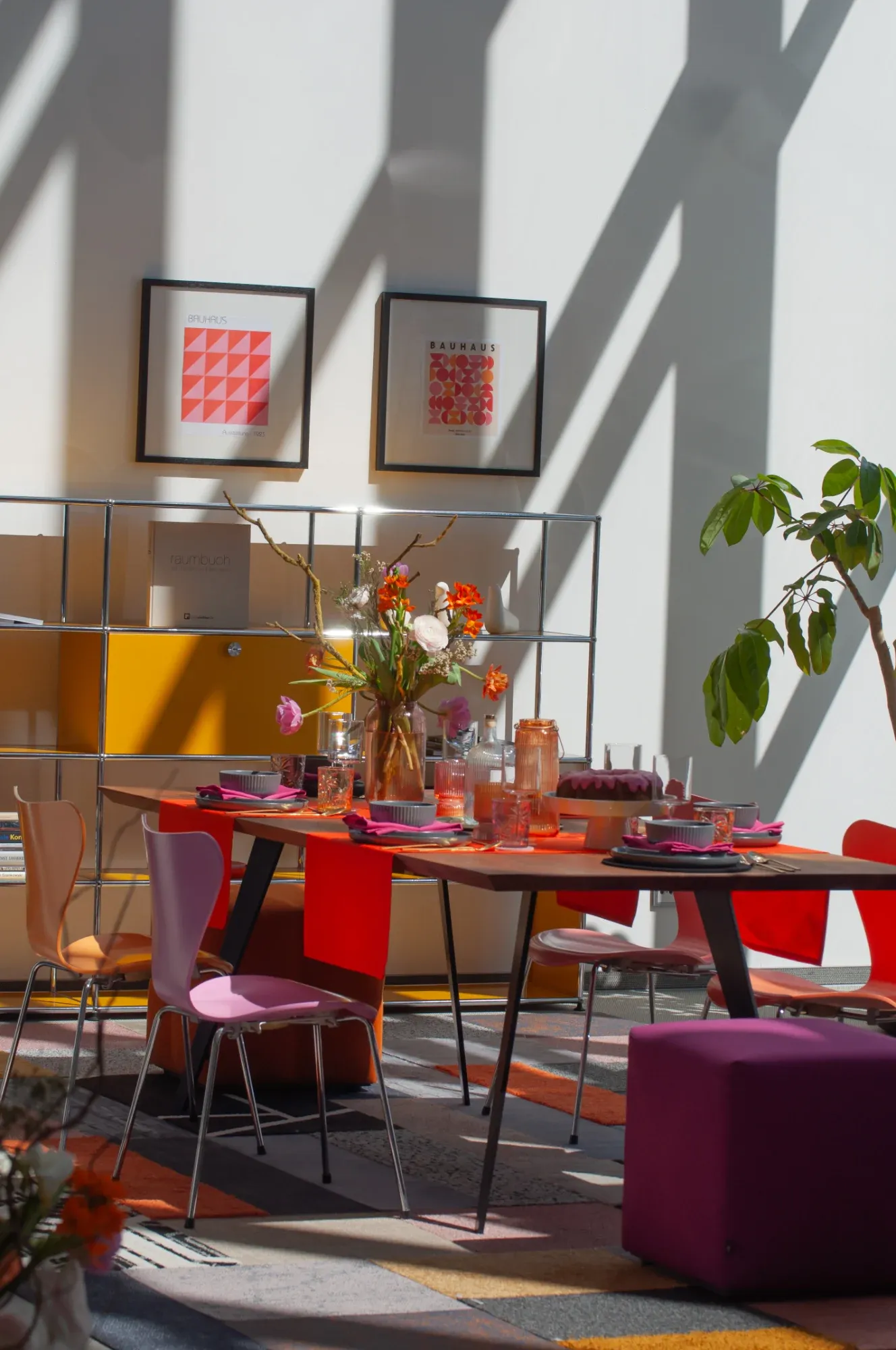 Blick von oben auf den Loungebereich mit Sofas, Teppich und Pflanzen an der Glasfassade, USM