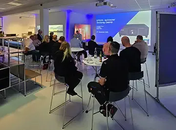 Teilnehmende im blau ausgeleuchteten Schulungsraum vor der Workshop-Präsentation