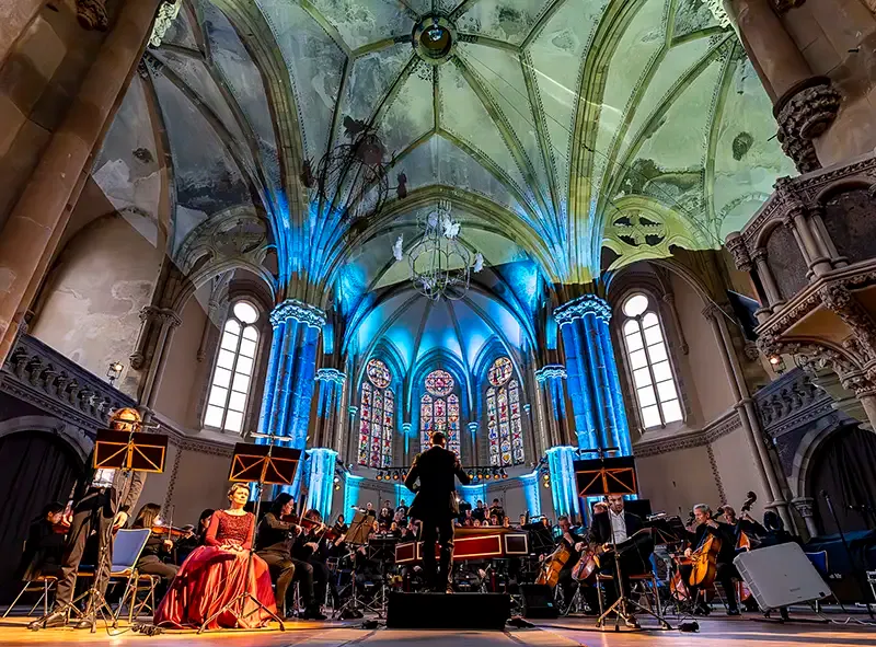 Blau angestrahltes Kirchenschiff mit Orchester und Solistin