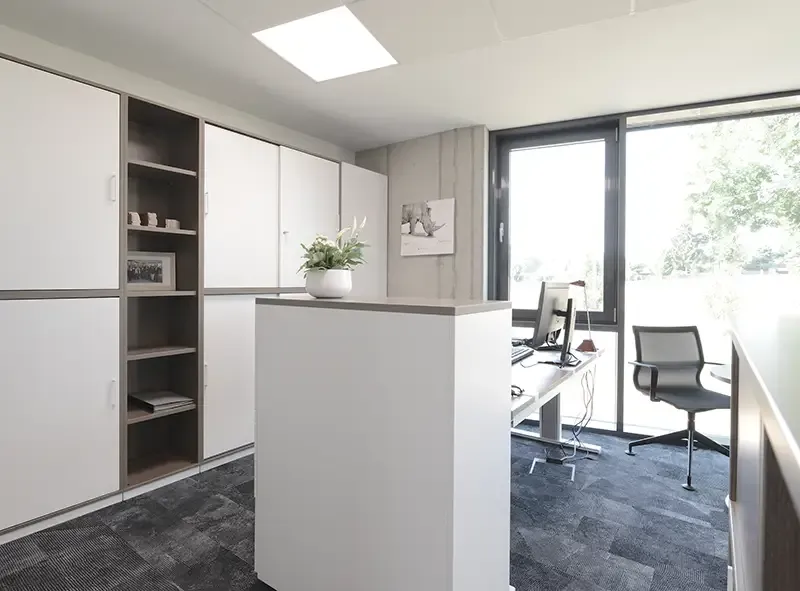 Bürozeile mit weißer Schrankwand und Arbeitsplatz am Fenster