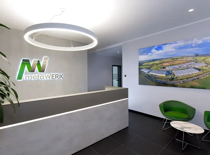 Empfangstheke mit beleuchtetem metaWERK-Logo und Luftbild an der Wand