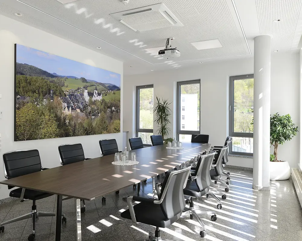 Konferenzraum mit langem Tisch, Beamer und großformatigem Landschaftsbild