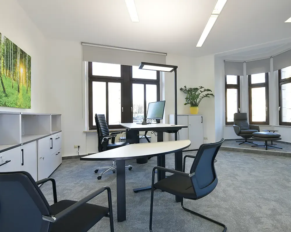 Büro mit höhenverstellbarem Schreibtisch, Besprechungstisch und Waldbild
