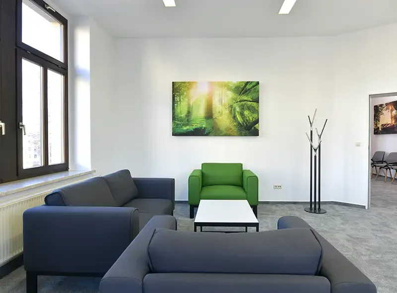 Loungebereich mit grauen Sofas und grünem Sessel am Fenster
