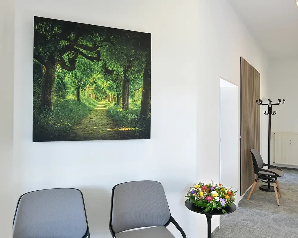 Wartebereich mit großformatigem Waldbild, Stühlen und Garderobenständer