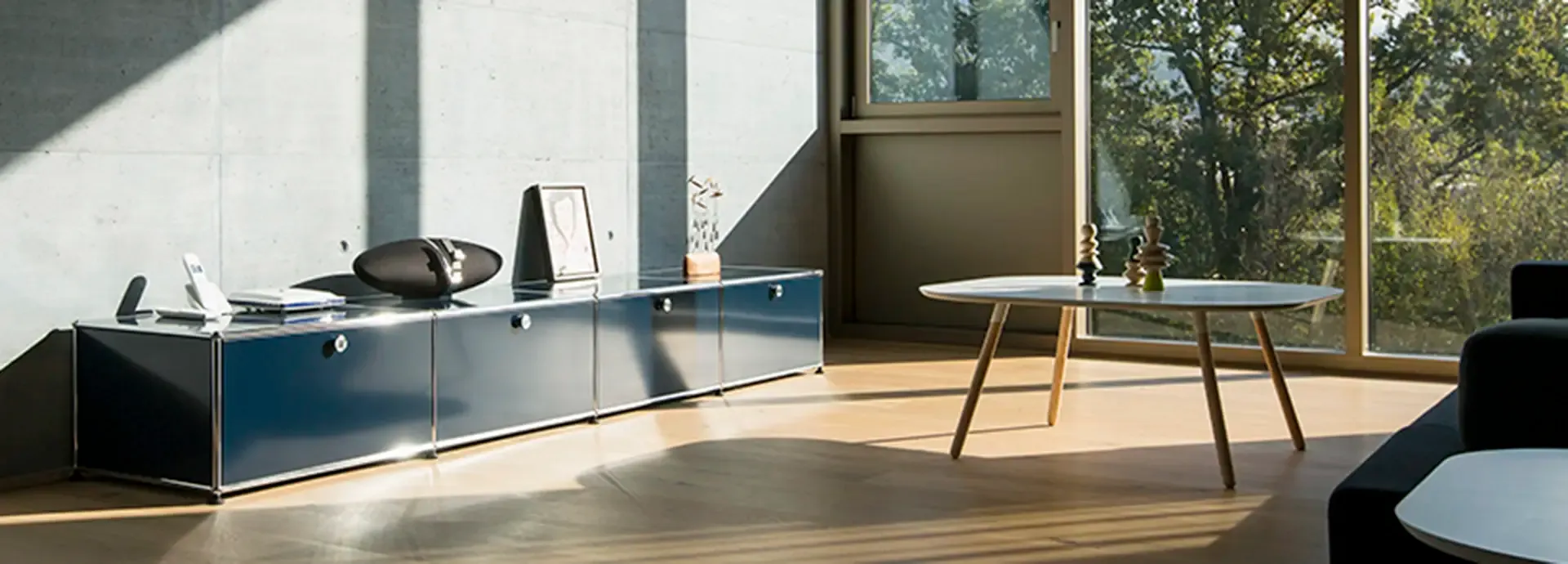 Dunkelblaues USM-Haller-Sideboard in einem Raum mit Sichtbetonwand