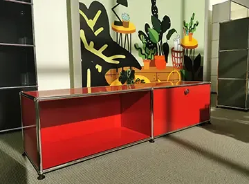 Rotes USM-Haller-Sideboard vor einer illustrierten Wand in der Ausstellung