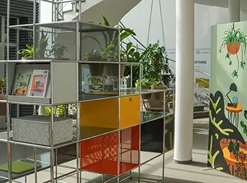 Bepflanztes Regalsystem mit farbigen Klappen in der Ausstellung