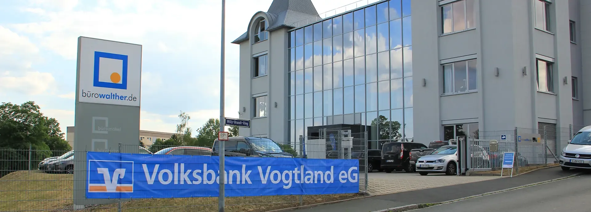 Firmengebäude mit Glasfassade, davor ein Banner der Volksbank Vogtland eG