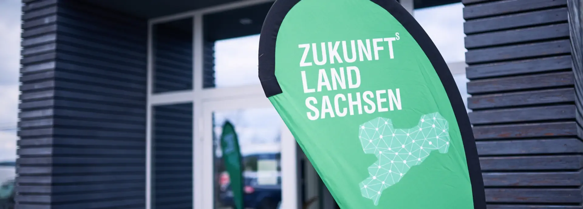 Grüne Beachflag „Zukunftland Sachsen“ vor dem Eingang
