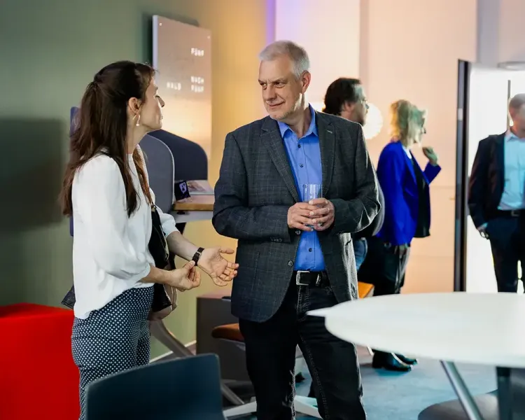 Zwei Gäste im Gespräch beim Empfang, im Hintergrund weitere Besucher