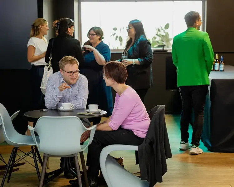 Gäste an Tischen und in Sitzgruppen während der Pause