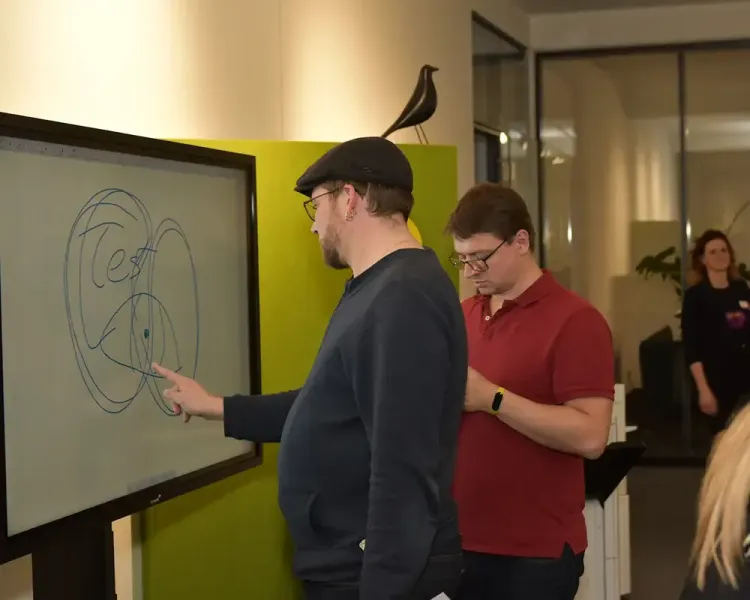 Zwei Besucher an einem digitalen Whiteboard mit einer Skizze