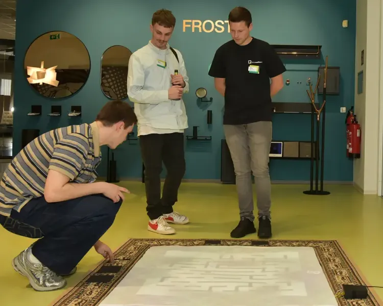 Drei junge Besucher betrachten eine Bodenprojektion auf einem Teppich