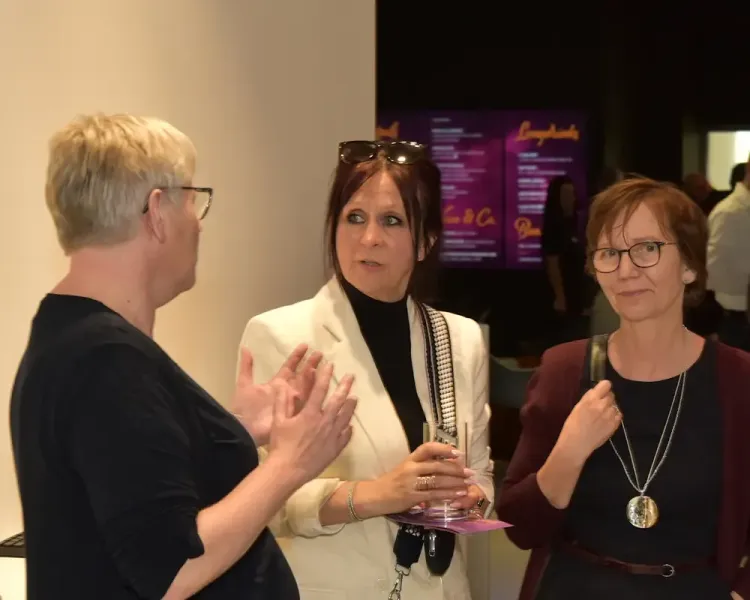Drei Besucherinnen im Gespräch, im Hintergrund die Cocktailkarte