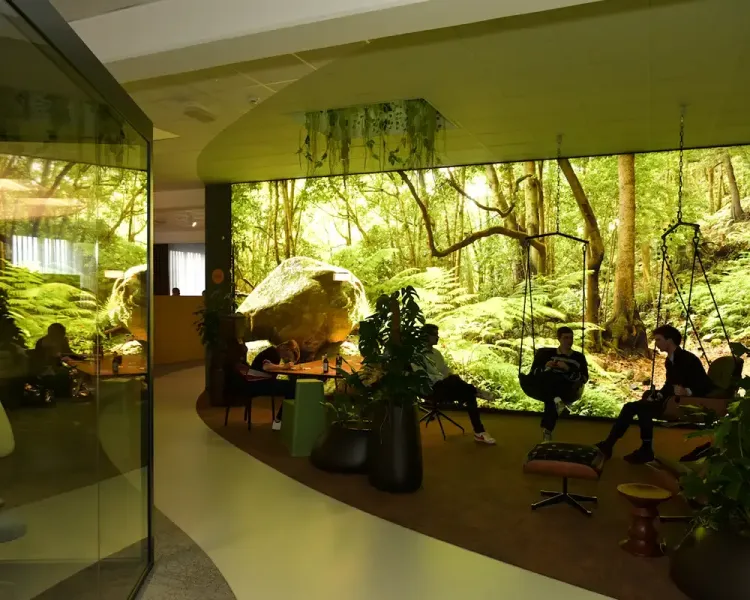 Blick in den begrünten Loungebereich mit Waldtapete und Hängesesseln