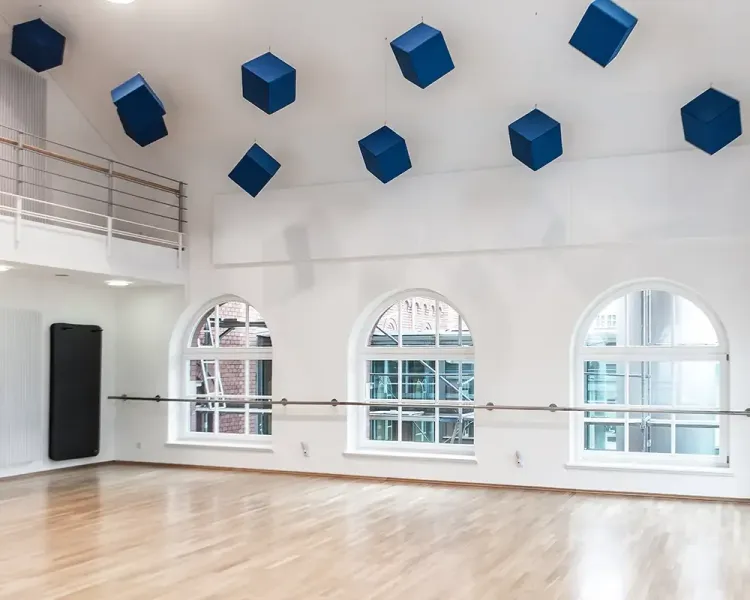 Gymnastikraum mit Ballettstange, Spiegelwand und blauen Akustikwürfeln unter der Decke