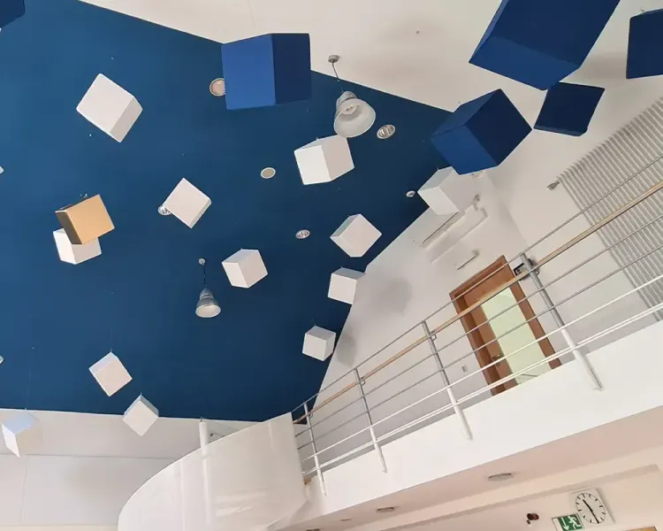 Blaue Decke mit Akustikwürfeln über der Galerie des Gymnastikraums