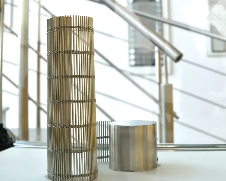 Zylinder aus Metallgewebe und eine Metalldose auf einer Ablage vor der Wendeltreppe
