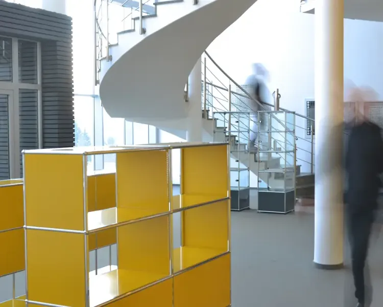 Gelbe USM-Haller-Möbel im Foyer unter der Wendeltreppe, Besucher in Bewegung
