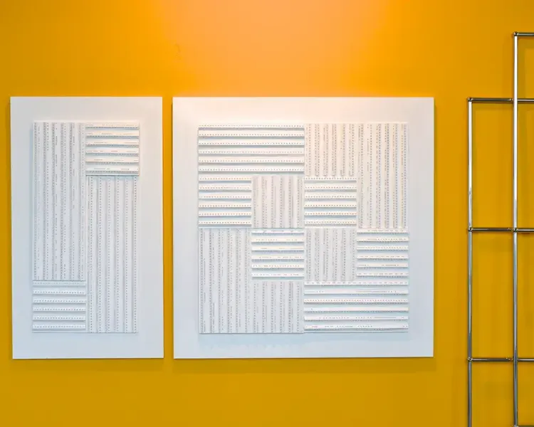 Zwei weiße Reliefbilder an oranger Wand, rechts ein verchromtes USM-Haller-Gestell