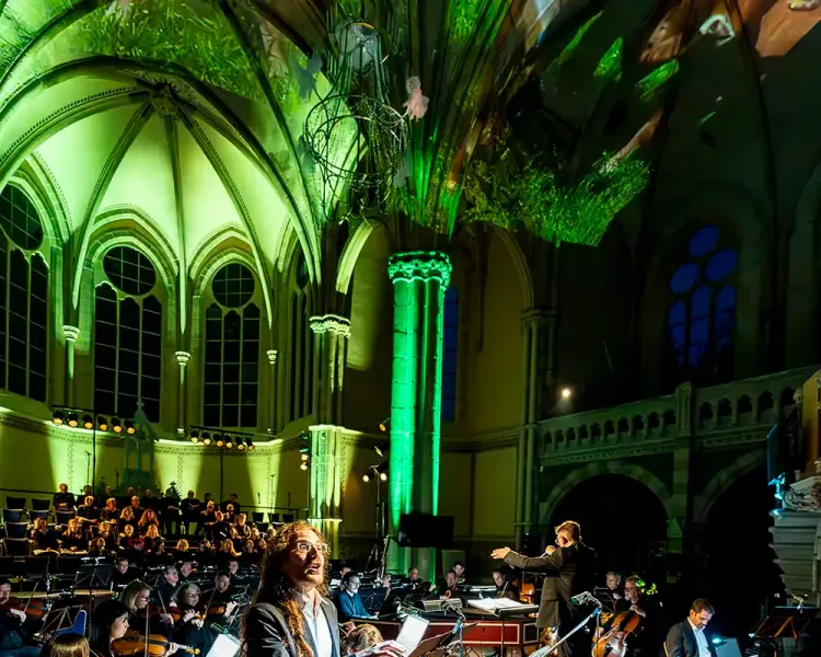 Beleuchtetes Kirchenschiff in Grün mit Orchester und Solistin