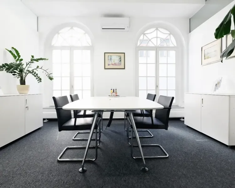 Besprechungsraum mit ovalem Tisch und Freischwingern vor Rundbogenfenstern