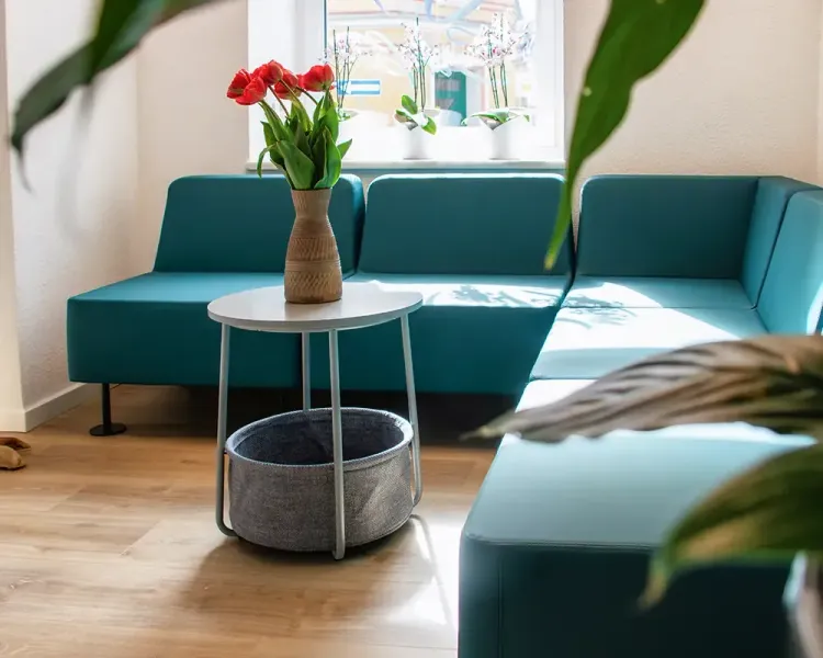 Wartebereich mit petrolfarbenen Polstermodulen und Beistelltisch mit Tulpen