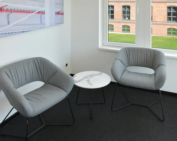 Zwei graue Loungesessel mit Marmor-Beistelltisch am Fenster
