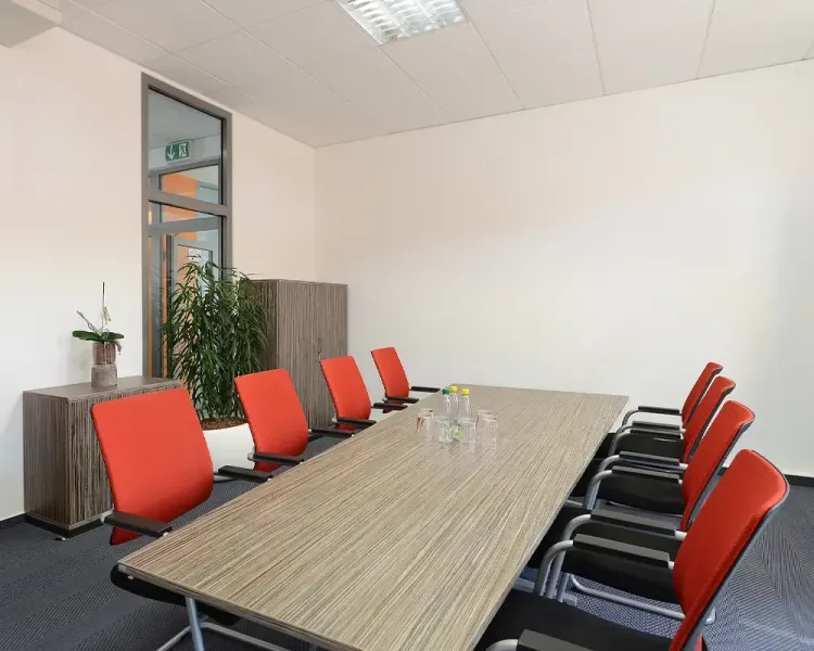 Besprechungsraum mit langem Tisch und roten Freischwingern