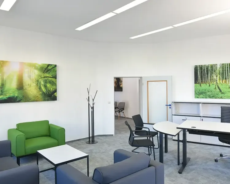 Büro mit grünem Sessel, Sofagruppe und zwei Waldbildern