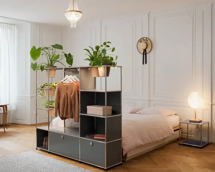 Regal als Raumteiler mit Pflanzen und Kleiderstange vor einem Bett