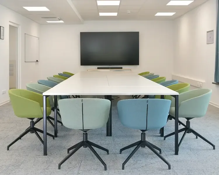 Besprechungsraum mit U-förmiger Tafel, Polstersesseln und großem Bildschirm