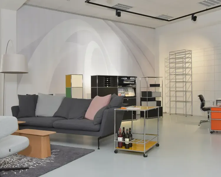 Wohnliche Ausstellungsszene mit Sofa, Barwagen und schwarzem Sideboard