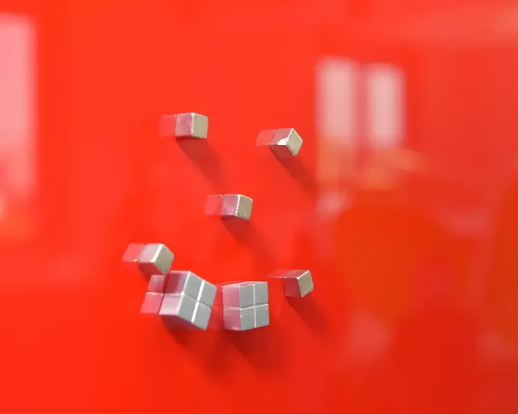 Silberne Würfelmagnete auf einer roten Glastafel