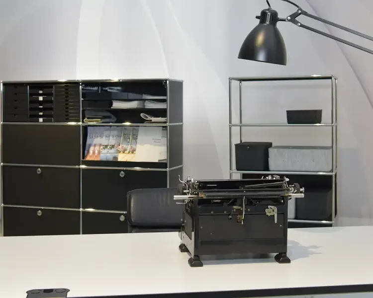 Alte Schreibmaschine auf einem Schreibtisch vor schwarzem USM-Haller-Sideboard
