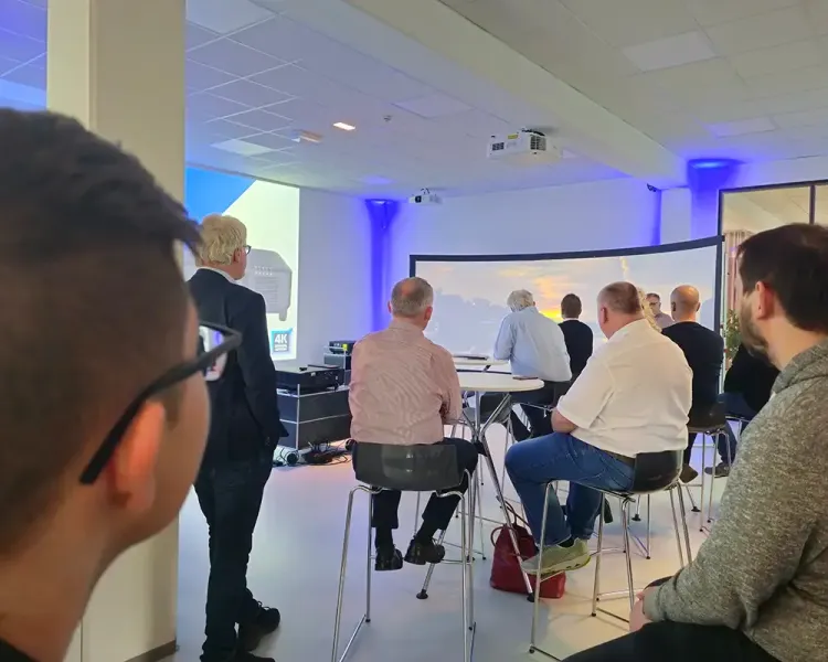 Teilnehmende des Epson-Workshops verfolgen die Projektion auf der gebogenen Leinwand