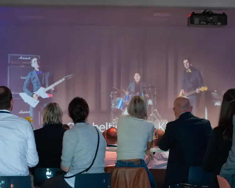 Publikum vor einer großen Bühnenprojektion mit Band