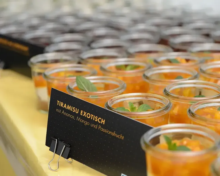 Dessertgläser am Buffet mit dem Schild „Tiramisu exotisch mit Ananas, Mango und Passionsfrucht“