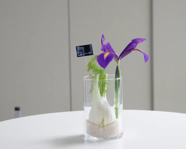 Tischdekoration aus Iris und Fenchel im Glas mit kleinem Firmenschild