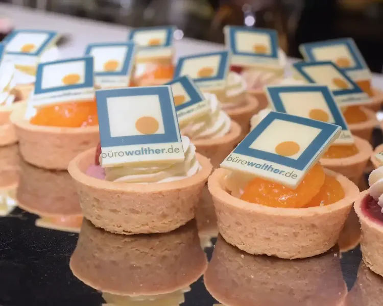Törtchen am Buffet, jedes mit einem Schokoschild „bürowalther.de“