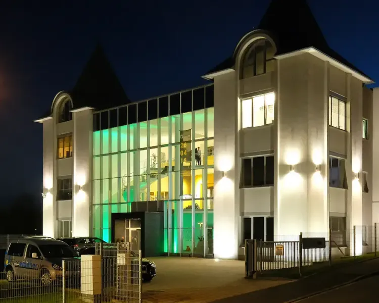 Firmengebäude bei Nacht mit grün beleuchtetem Glasfoyer