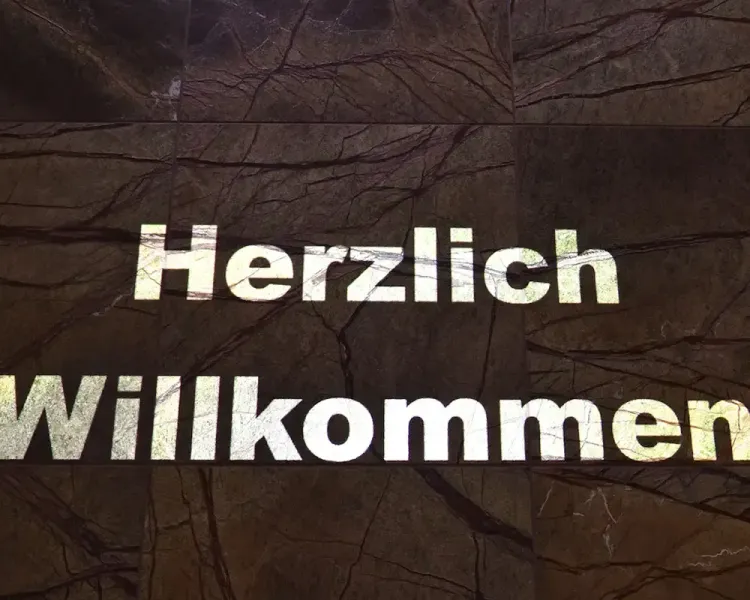 Bodenprojektion mit dem Schriftzug „Herzlich Willkommen“ auf Marmor