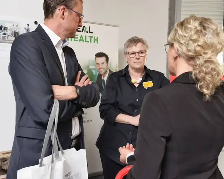 Vier Personen im Gespräch vor einem Rollup zum Thema Gesundheit
