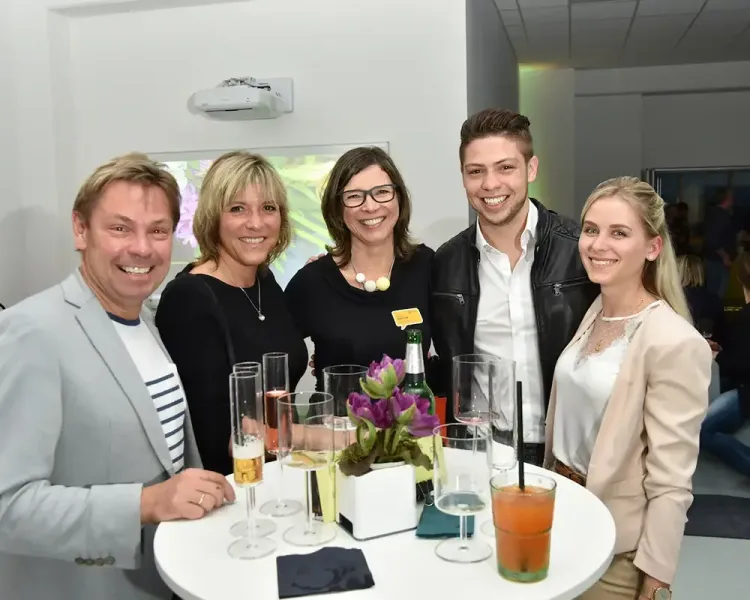 Fünf Gäste an einem Stehtisch mit Sekt und Cocktails