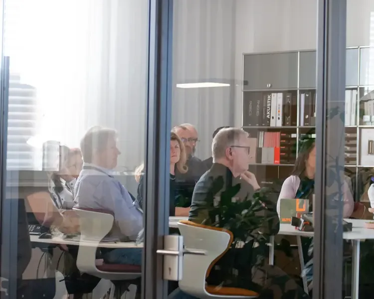 Blick durch die Glastür auf eine Schulung mit Teilnehmenden